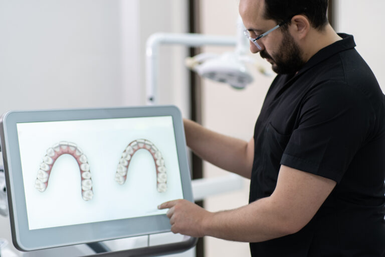 skilled dentist showing lower and upper human jaws models on monitor presenting teeth treatment